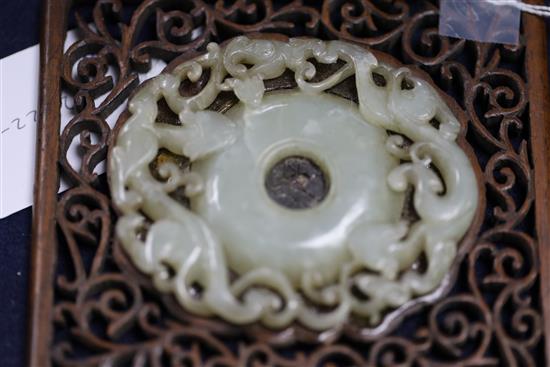 A Chinese archaistic pale celadon jade bi disc, 17th/18th century, Jade 8.3cm, frame 11cm x 12cm